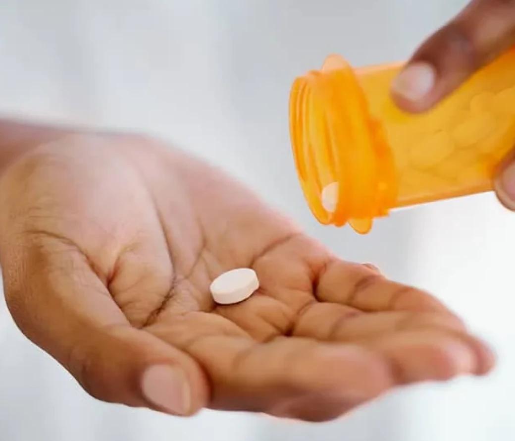 Person pouring pills into their palm from a bottle