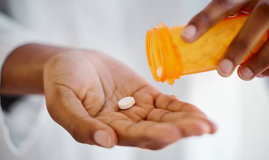 Person pouring pills into their palm from a bottle